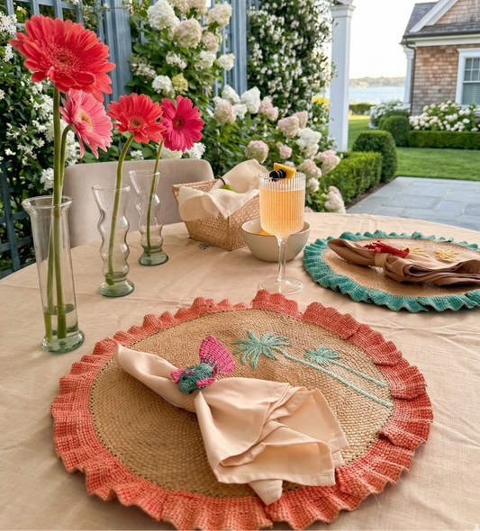 Decorative table setting with floral arrangements, placemats, and folded napkins in an outdoor setting.