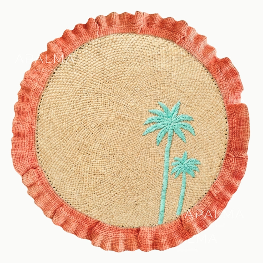Round woven mat with coral border and turquoise palm tree design on a white background